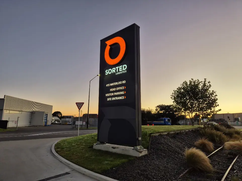 Illuminated roadside pylon featuring directional signage for Sorted Logistics