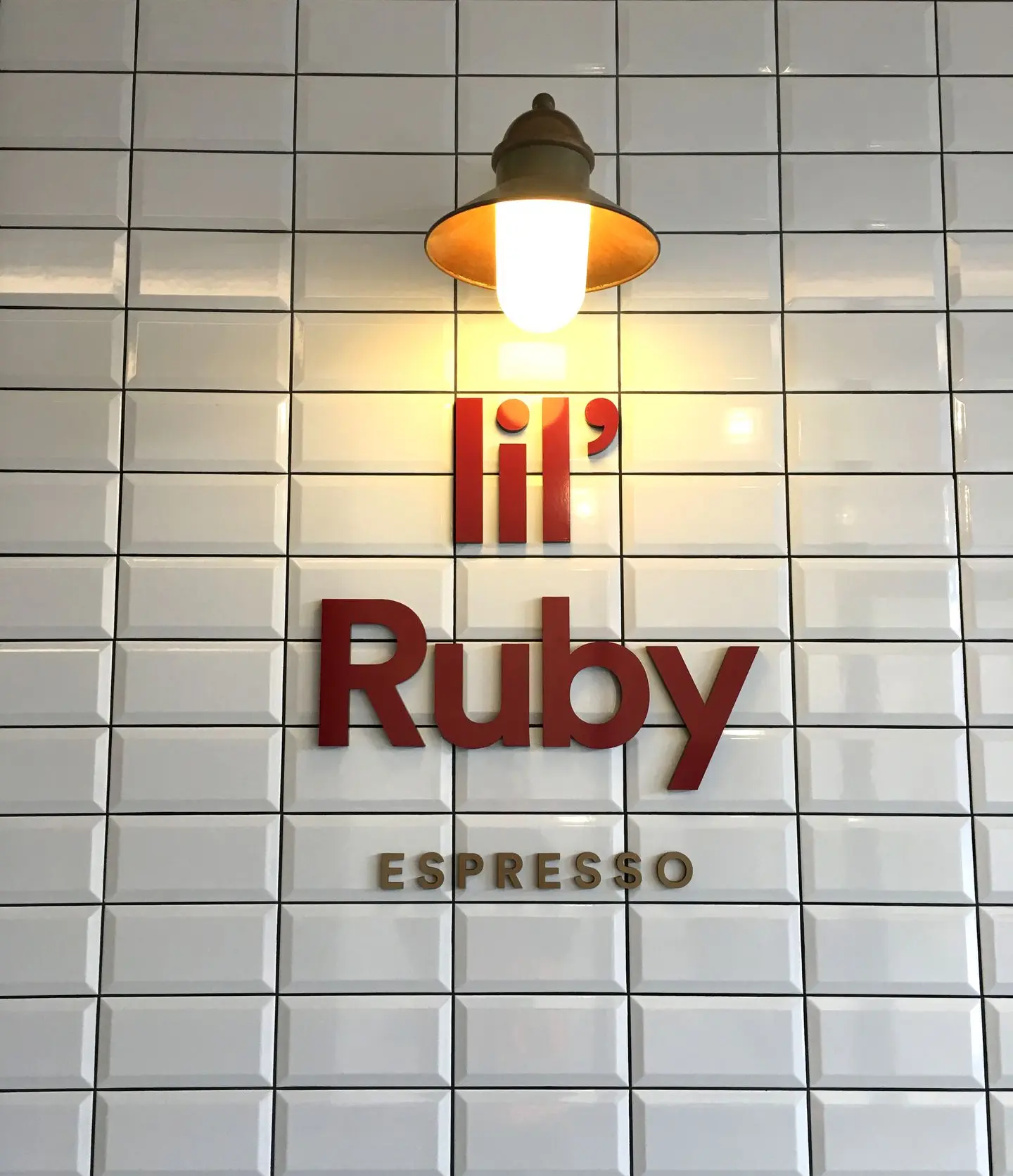 Custom cut lettering on white tiled wall for Lil Ruby coffee store interior.