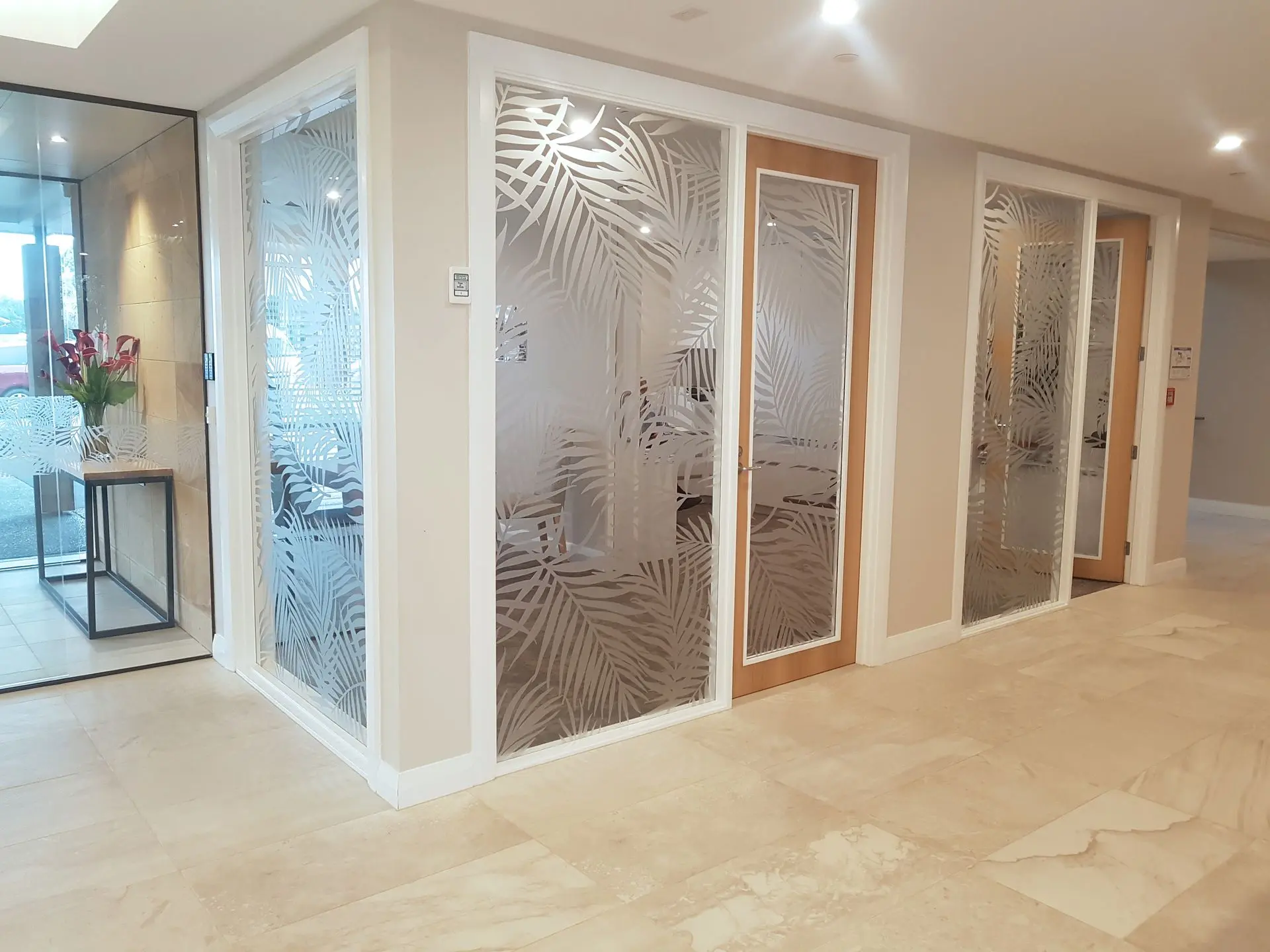This frosted window graphics features fern fronds across glass windows and doorways in this office space.